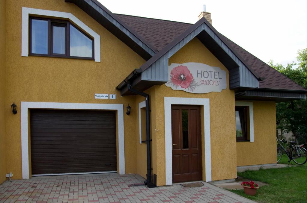 a house with a hotel sign and a garage at Guest House Magones in Preiļi