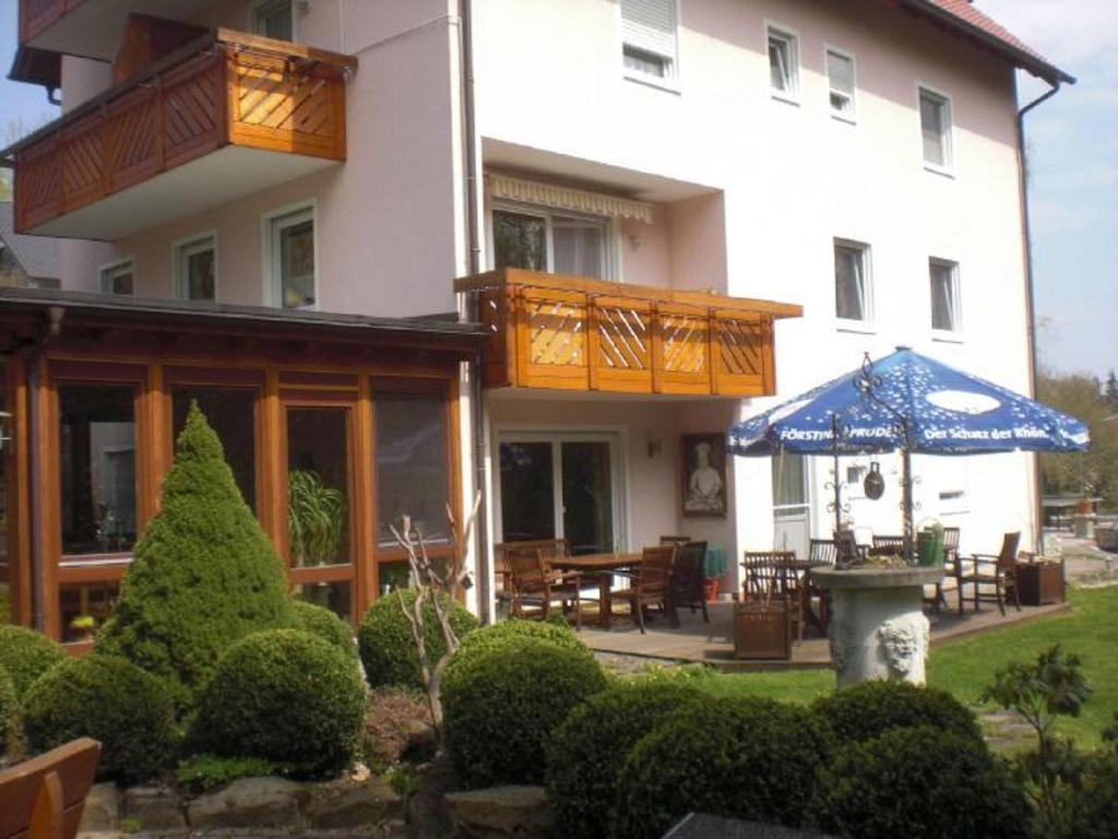 a large white building with a patio and an umbrella at Pension Haus am Heubach in Bad Staffelstein