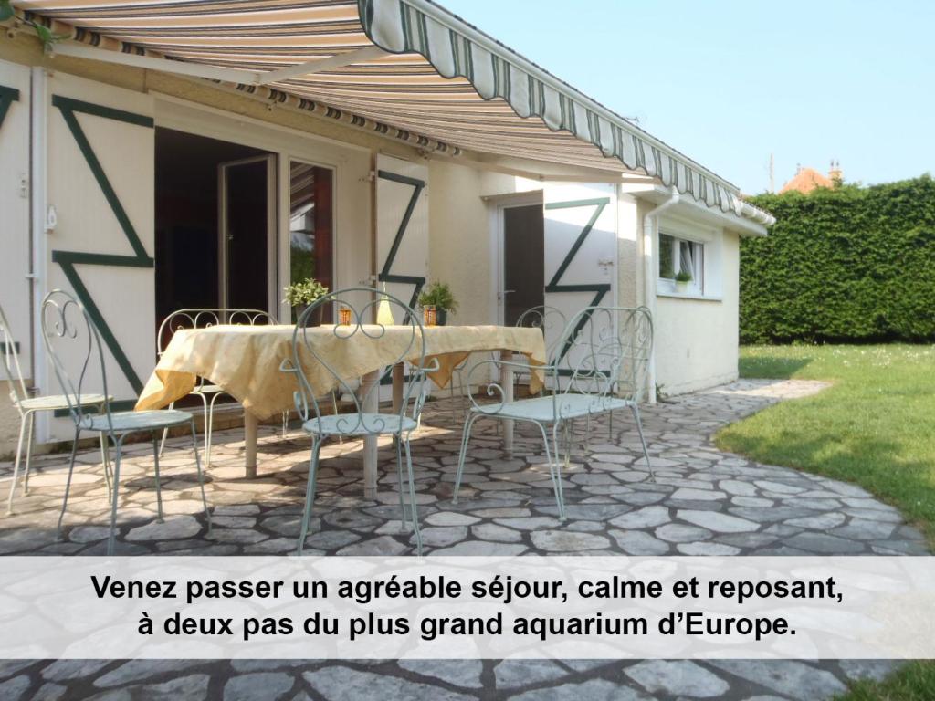 a patio with a table and chairs in front of a house at Au cèdre bleu in Saint-Martin-Boulogne
