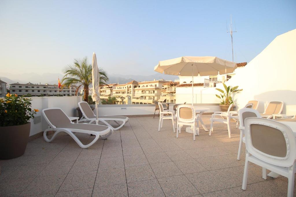 a group of chairs and an umbrella on a patio at Hotel Puerta del Mar - Adults Recommended in Nerja