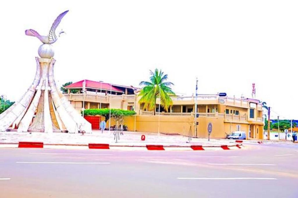 a building with a statue in the middle of a parking lot at Hôtel Saint Thomas in Lomé