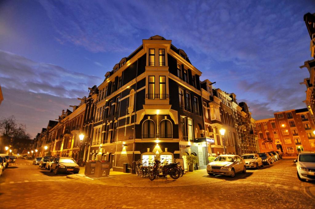 un gran edificio con coches estacionados frente a él en Hotel Parkview en Ámsterdam