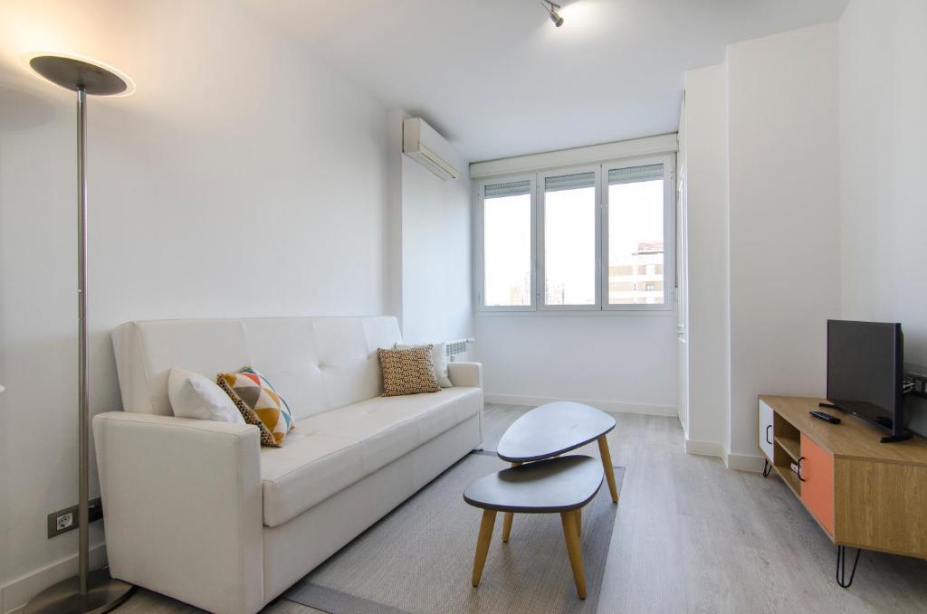 a white living room with a white couch and a table at Minty Stay- 1BD in Madrid