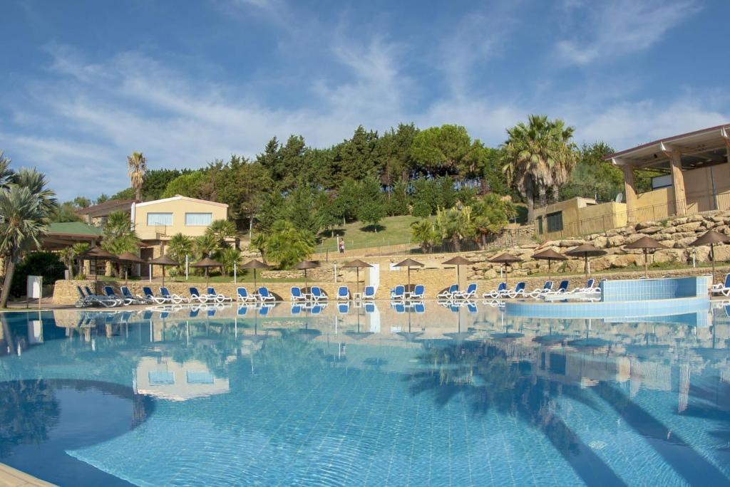 una gran piscina con sillas y sombrillas en TH Le Castella - Baia degli Dei Village, en Le Castella