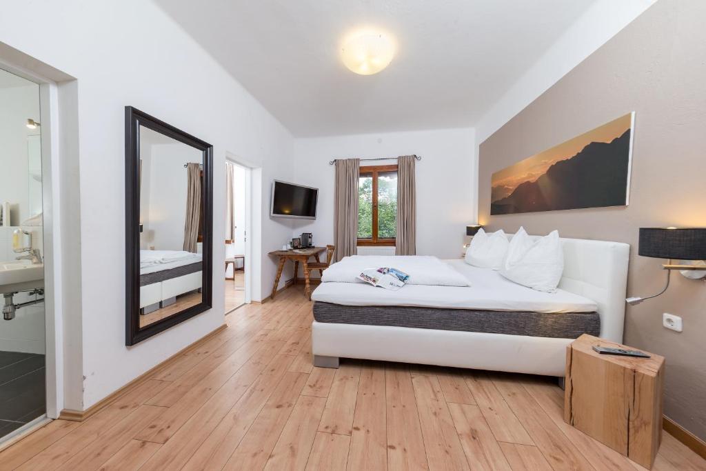 a bedroom with a large white bed and a bathroom at Alpenhaus Kesselfall in Kaprun