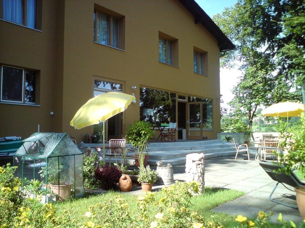 ein Haus mit einer Terrasse mit einem Tisch und einem Sonnenschirm in der Unterkunft Hotel Garni - Appartements Fuksas in Bad Gleichenberg