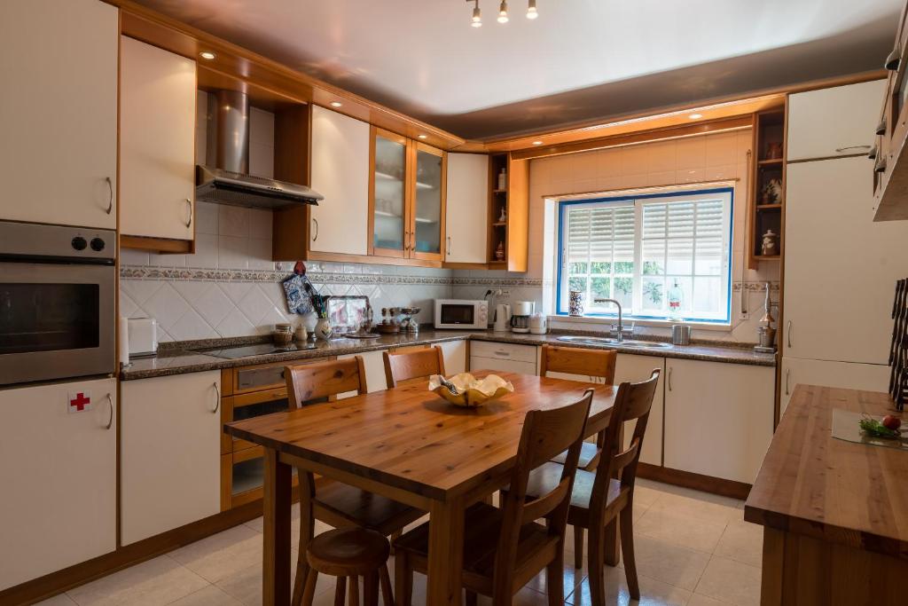 a kitchen with a wooden table with chairs and a sink at Casa das Conchas in Ericeira