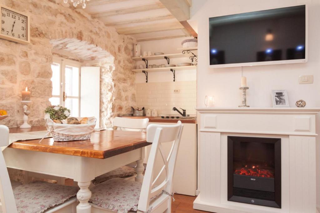 een keuken met een open haard, een tafel en een televisie bij Apartments Lufra Skradin in Skradin