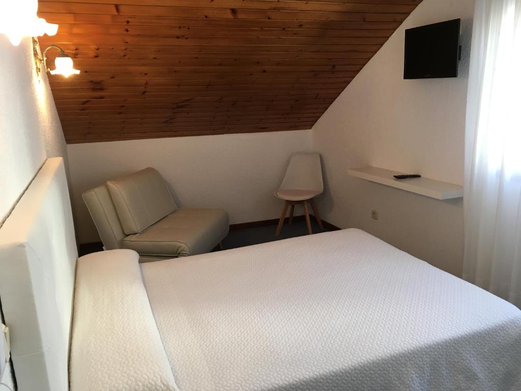 a bedroom with a white bed and a chair at Hotel Derli Sella in Ribadesella