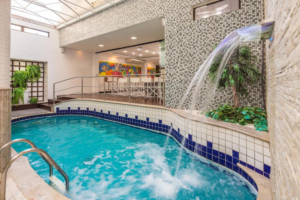 a pool with a water slide in a building at Hotel Torre Sol in Balneário Camboriú