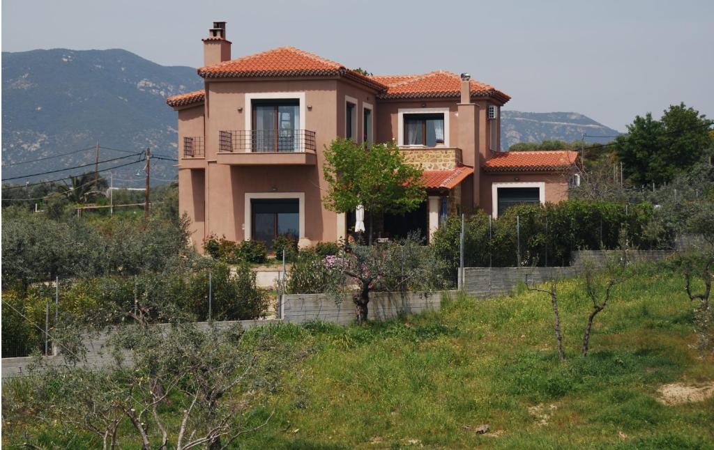 a house on a hill with a fence in front of it at Olive Tree Cottage in Nea Peramos