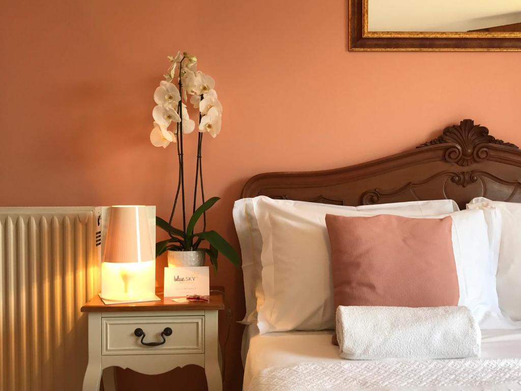 - une chambre avec un lit et une table de chevet avec une lampe et des fleurs dans l'établissement B&B Moon light - Bedbluesky, à Perinaldo