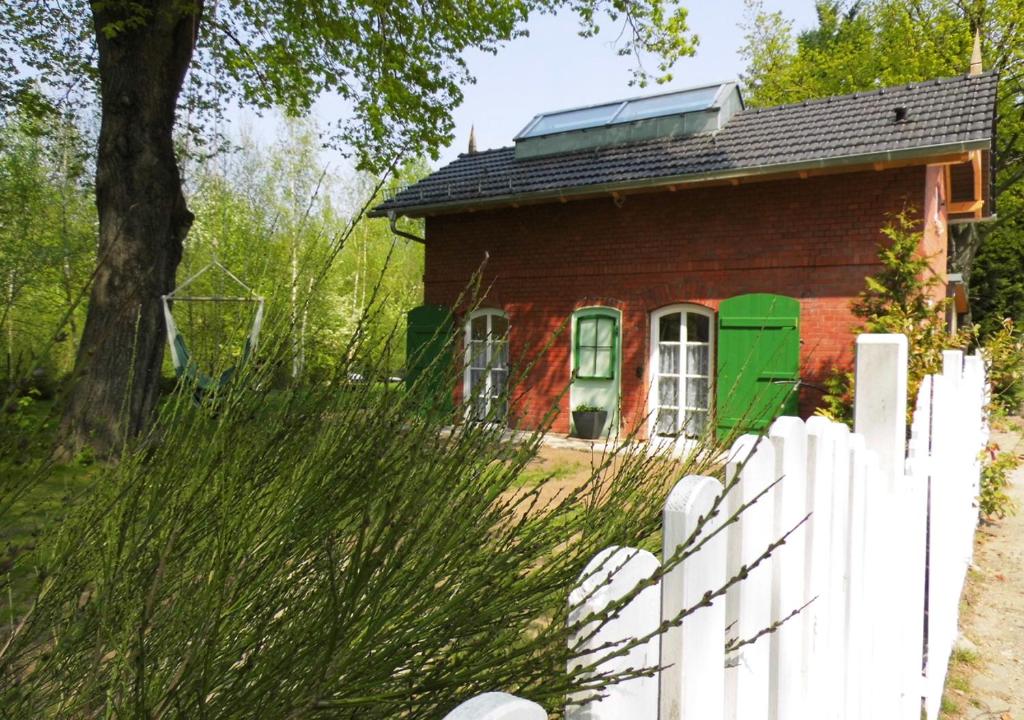 ein rotes Haus mit einem weißen Zaun davor in der Unterkunft Bahnhof Droyßig - Übernachten im Denkmal in Droyßig