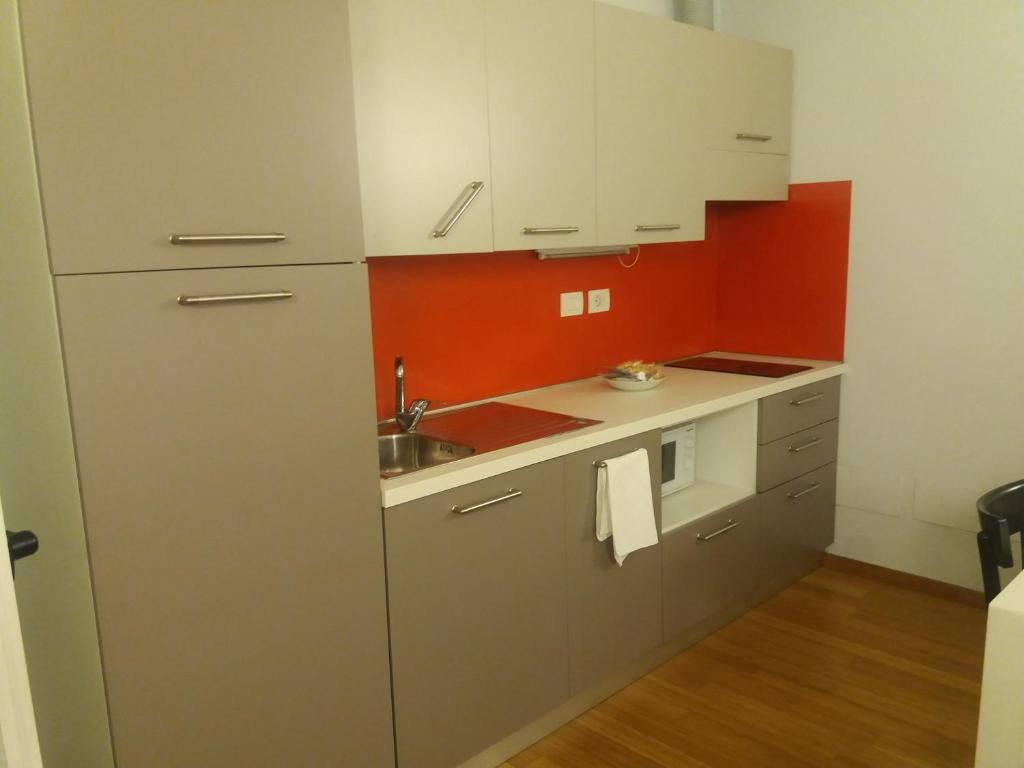 małą kuchnię z białymi szafkami i zlewem w obiekcie Luoghi Comuni Porta Palazzo w Turynie