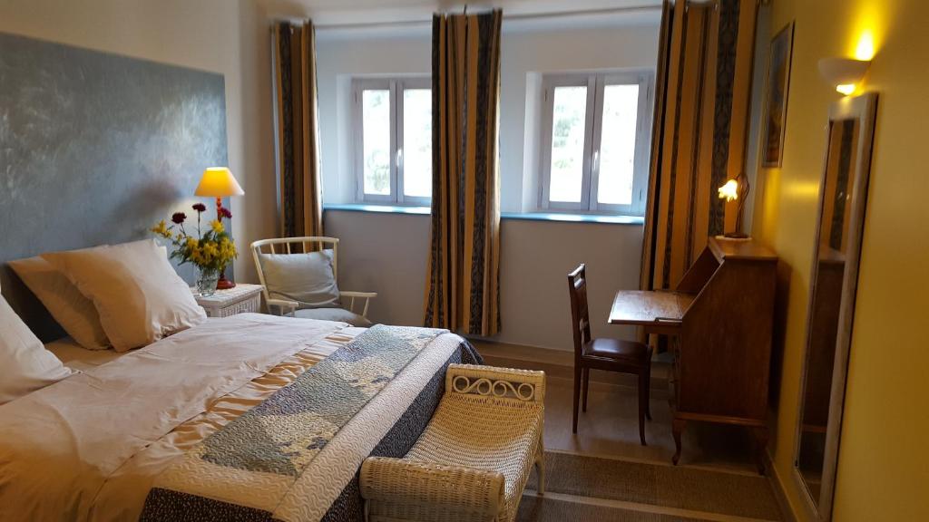 a bedroom with a bed and a desk and windows at L'Oliveraie des 3 Mas in Saint-Michel-de-Llotes