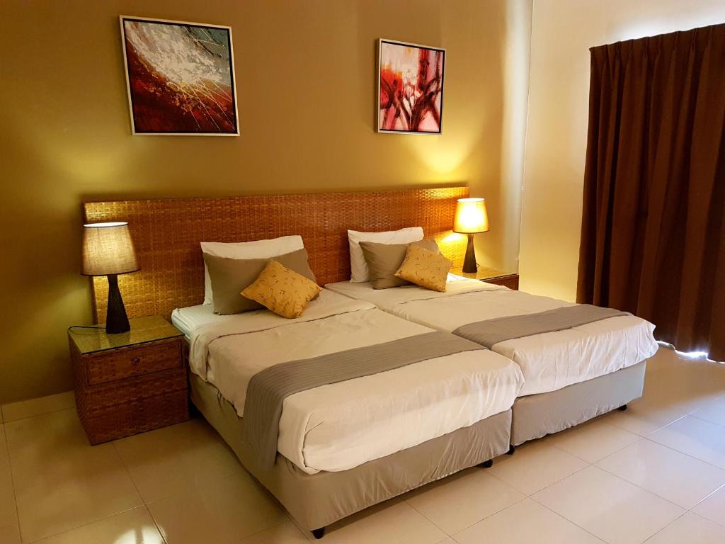 a bedroom with a large bed with two lamps at Cozy Escape @ Gold Coast Morib in Morib