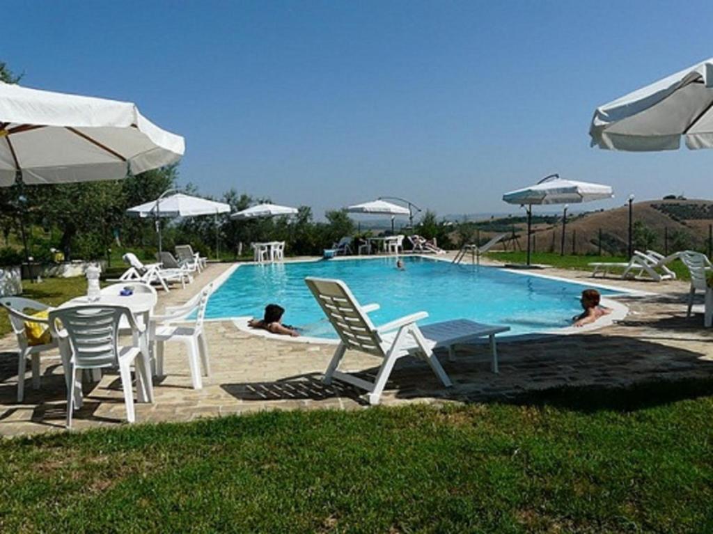 a pool with chairs and umbrellas and people laying in it at Agriturismo Il Portico in Penne