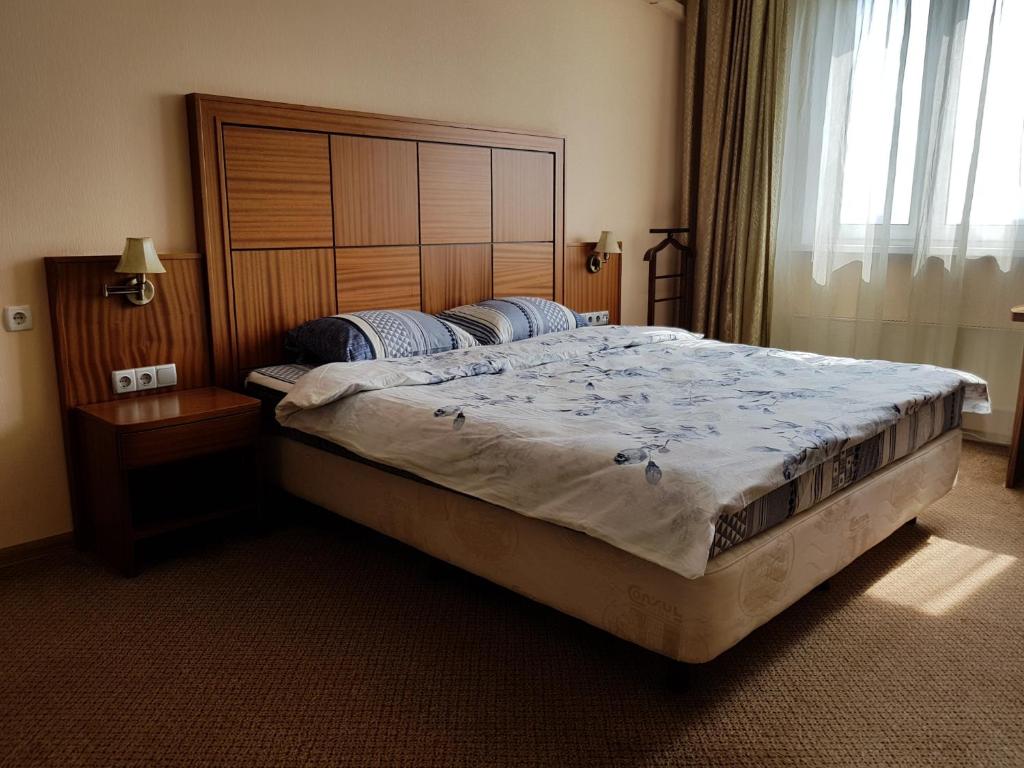 モスクワにあるDeluxe Apartment on Severnoe Chertanovoの大型ベッド1台(木製ヘッドボード付)が備わるベッドルームです。