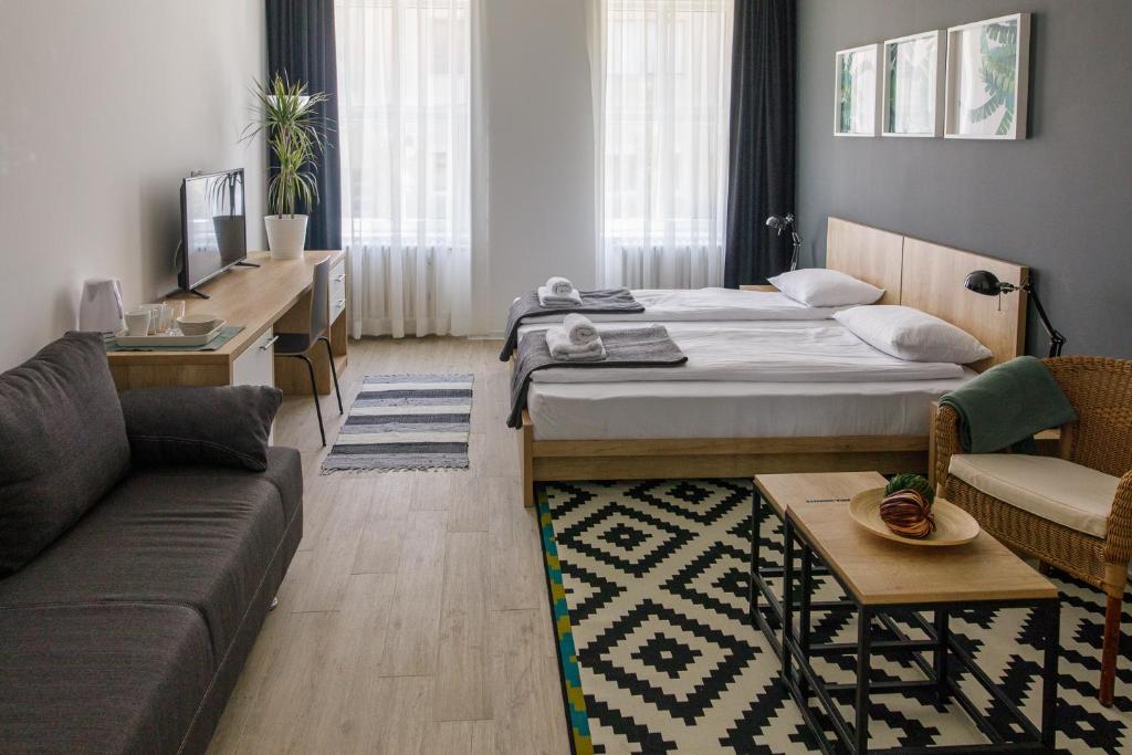 
a hotel room with a bed, couch, table and television at Arhiv Boutique House in Novi Sad
