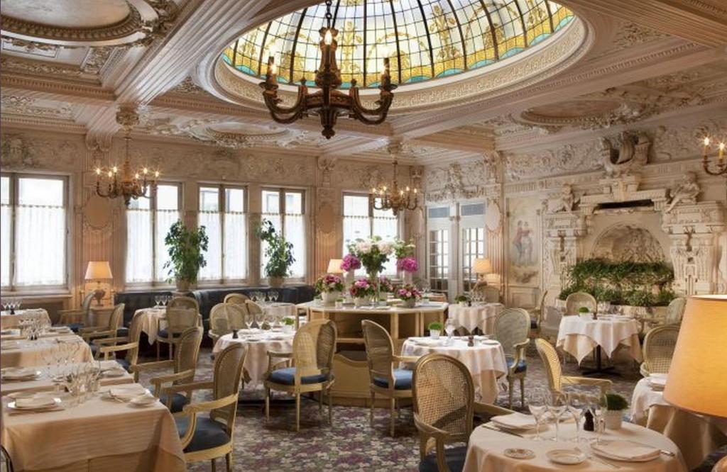 uma sala de jantar com mesas e cadeiras e um lustre em Hôtel Bedford em Paris