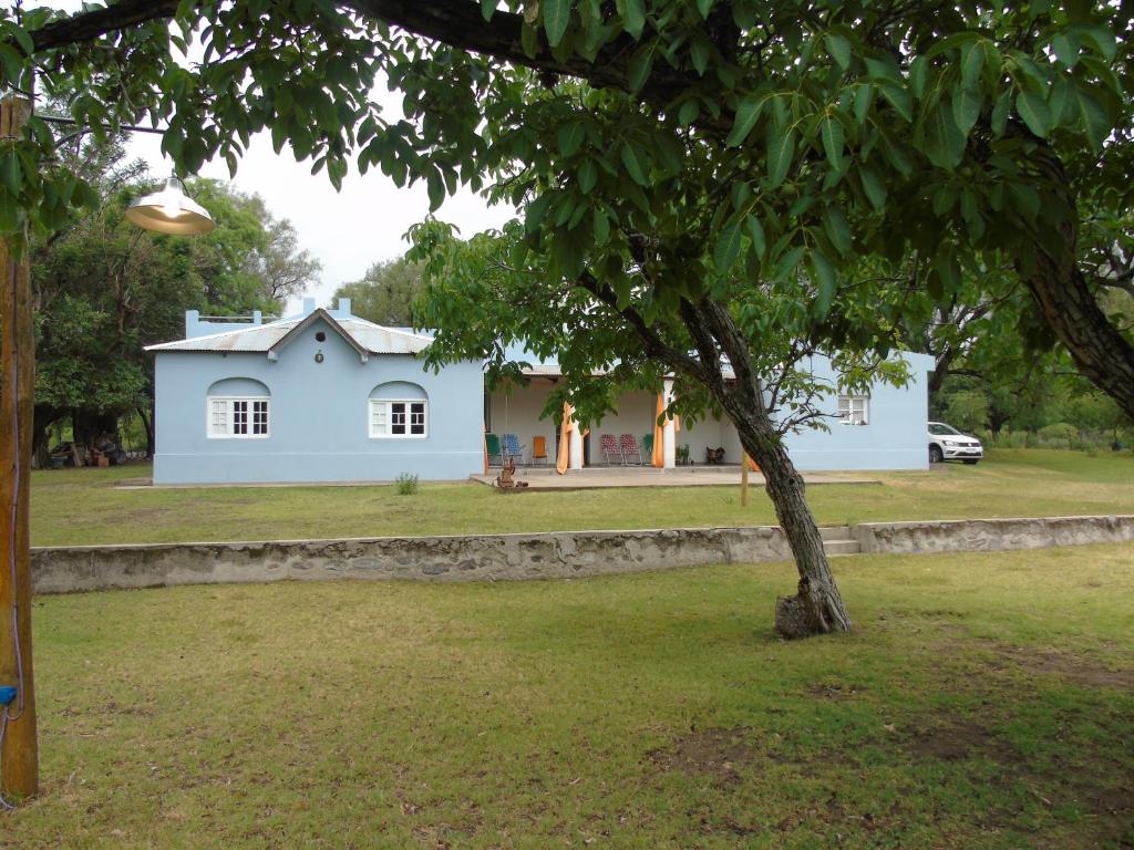 Una casa blanca con un árbol delante. en al otro lado del río in 