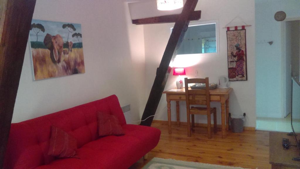 ein Wohnzimmer mit einem roten Sofa und einem Tisch in der Unterkunft La Ciboulette in Foix