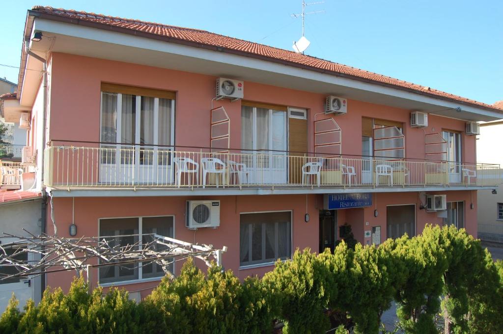ein rosafarbenes Gebäude mit Stühlen auf den Balkonen in der Unterkunft Hotel Aurora in Loano