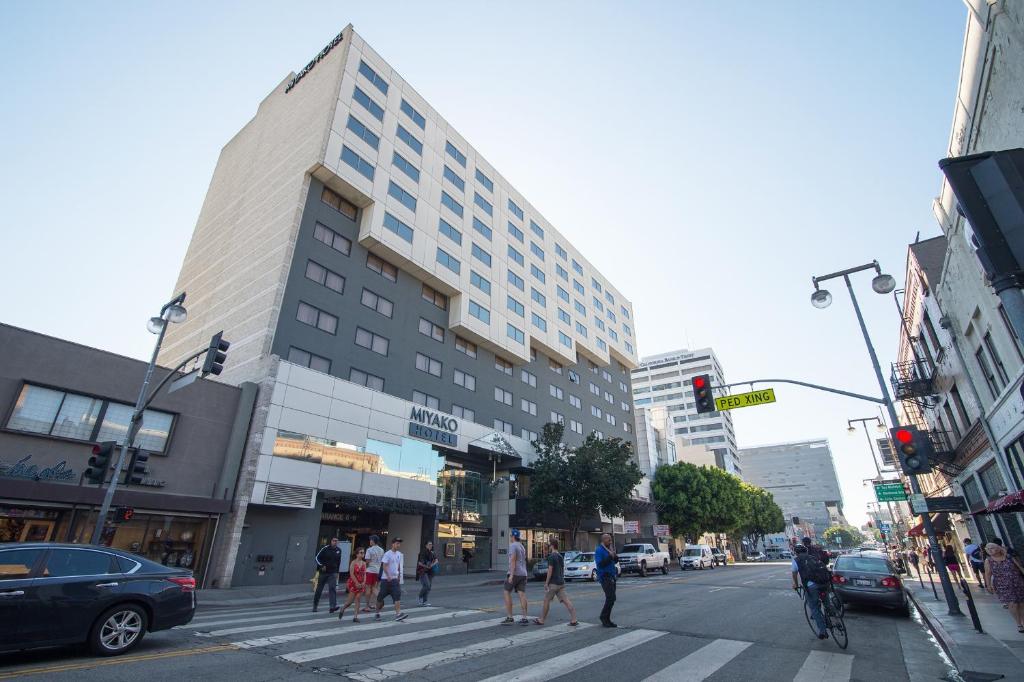 people crossing a street in a city with a building at Miyako Hotel Los Angeles in Los Angeles