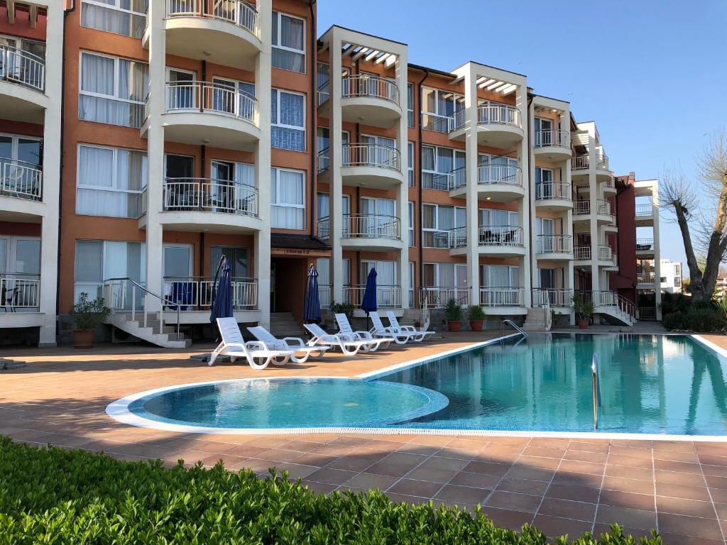 an apartment building with a swimming pool and chairs at Apartments Bellevue in Ravda