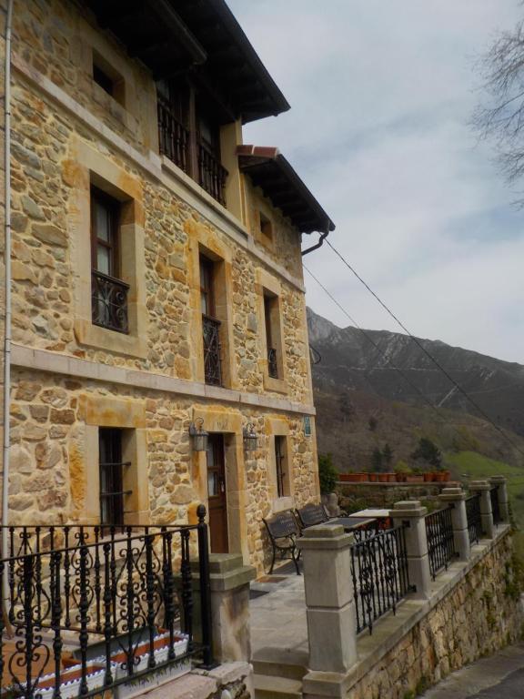 un edificio in pietra con balcone e recinzione di Apartamentos Rurales La Husteriza a Ruenes