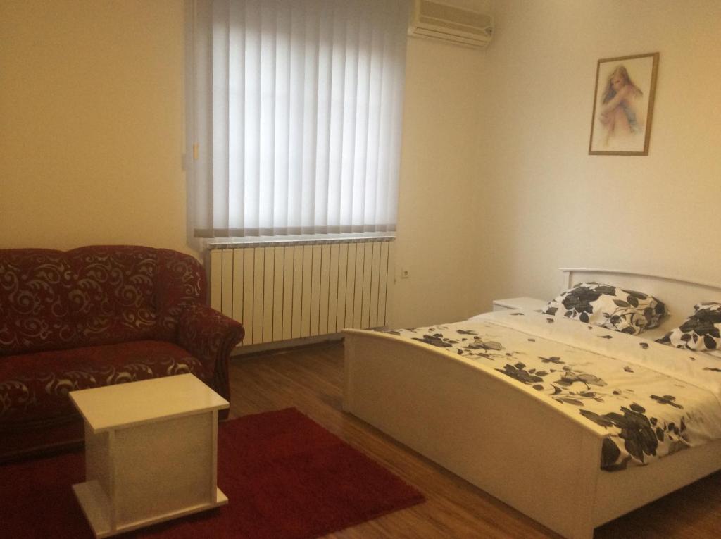 1 dormitorio con cama, sofá y ventana en Apartman br.1, en Bijeljina