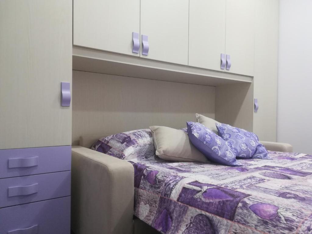 a bedroom with a bed with purple sheets and white cabinets at Attico Sole Luna in Taormina