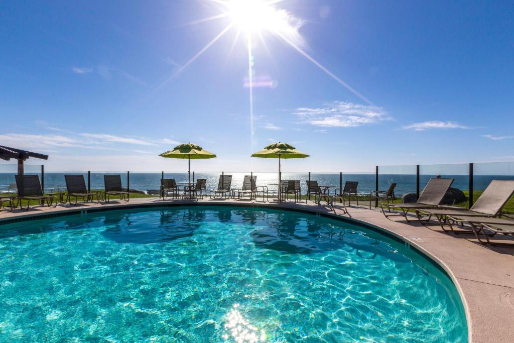 a pool with chairs and umbrellas on top of a building at Wave Crest Resort in San Diego