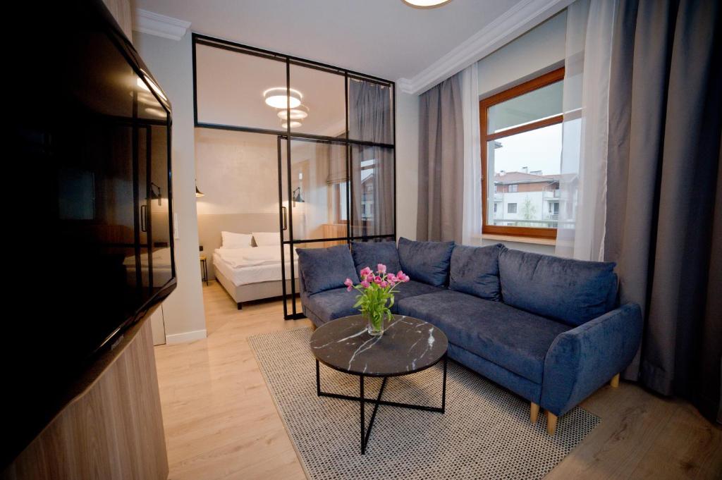 ein Wohnzimmer mit einem blauen Sofa und einem Tisch in der Unterkunft Lucy Apartment Neptun Park - Hav Aparts in Danzig