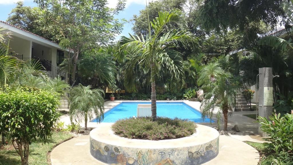 a pool with a palm tree next to a house at Coco Beach Home in Coco