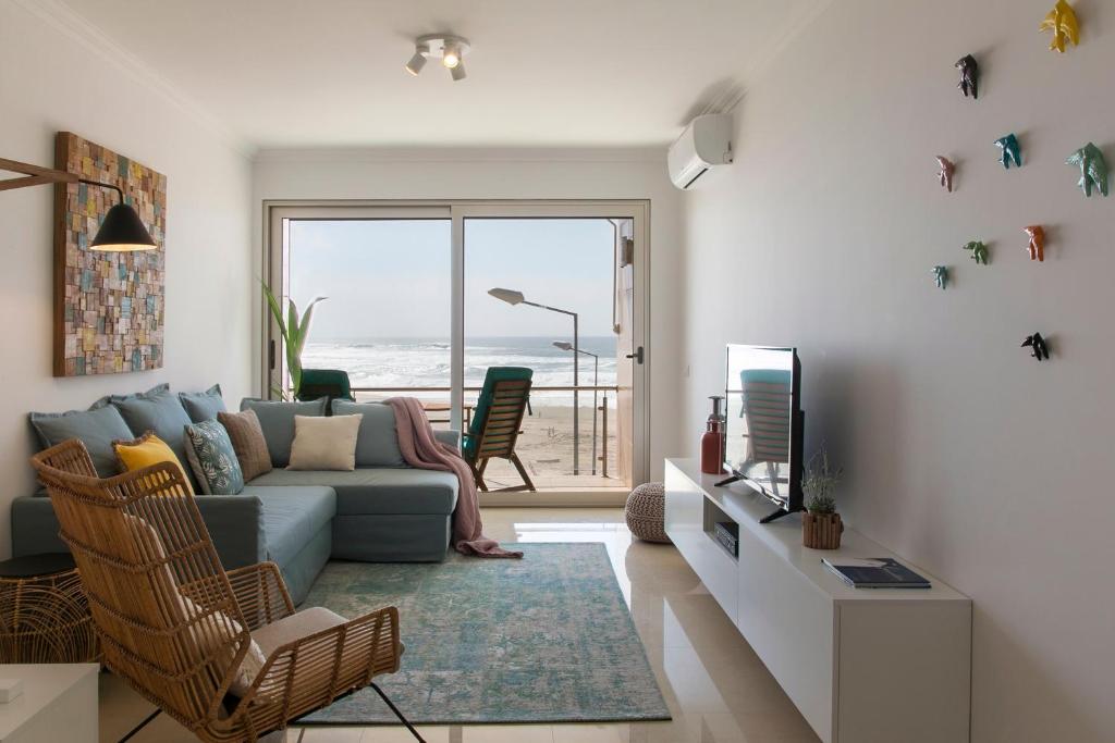 een woonkamer met een bank en een tv bij Silver Coast - Casa do Oceano in Foz do Arelho