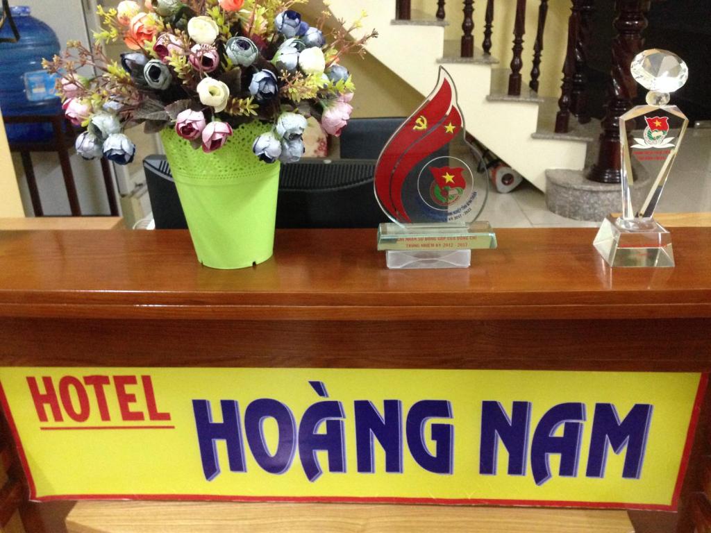 Un panneau qui dit hôtel hong km avec un vase de fleurs dans l'établissement Hoang Nam Hotel, à La Gi