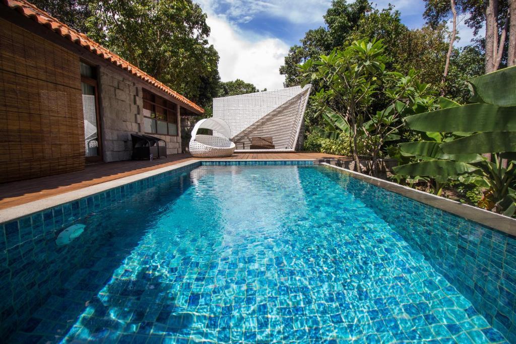 Arumdalu Private Resort في Membalong: مسبح مع كرسي بجانب منزل