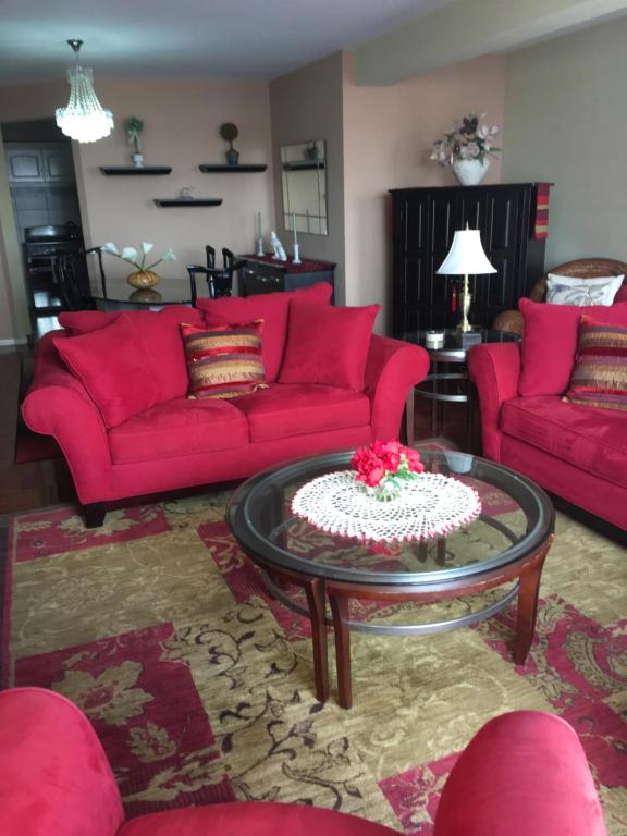 Elite Apartment في كوتشابامبا: غرفة معيشة مع أرائك حمراء وكعكة على طاولة