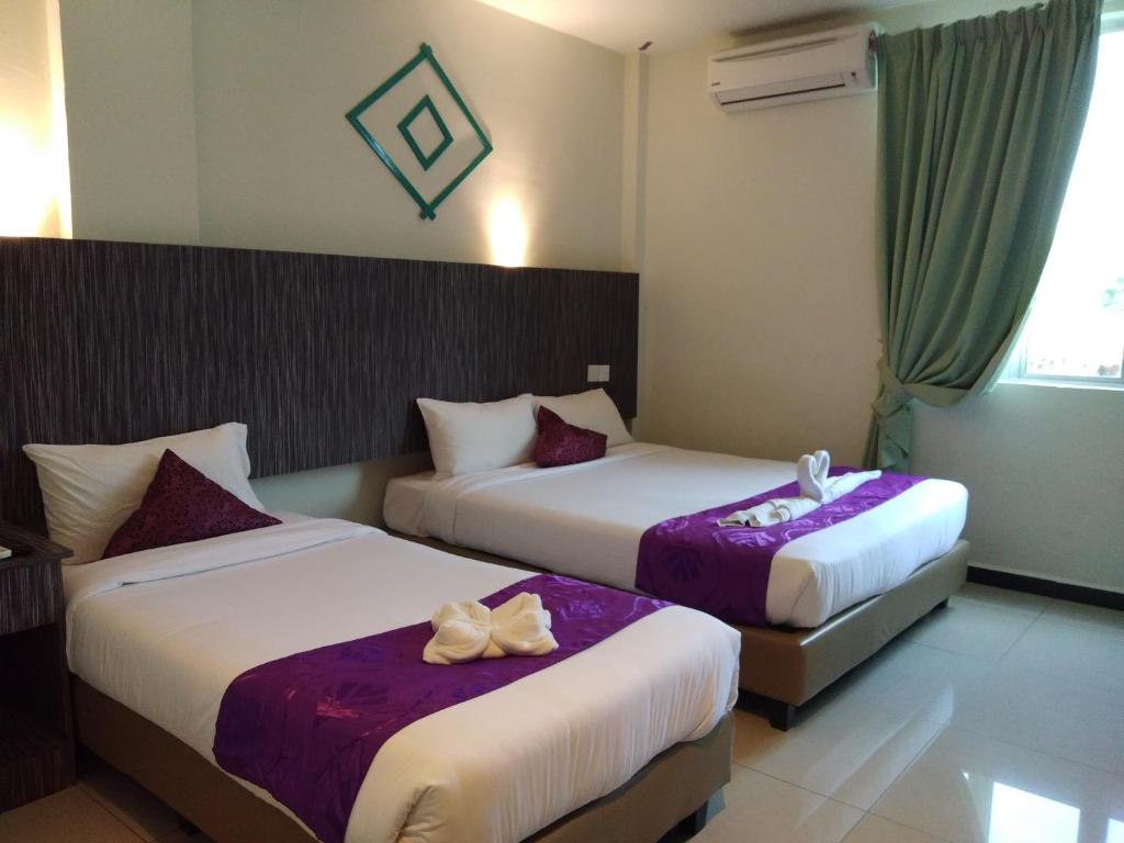 two beds in a hotel room with purple sheets at Salsa Resort Langkawi By Casa Loma in Pantai Cenang
