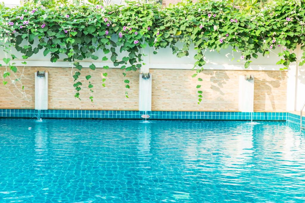 a swimming pool with plants on a brick wall at Lamai Coconut Beach Resort in Lamai
