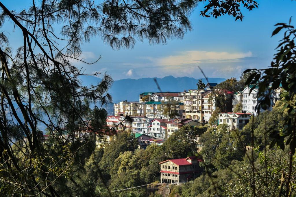 a town on a hill with mountains in the background at Dhanlaxmi Apartments in Shimla