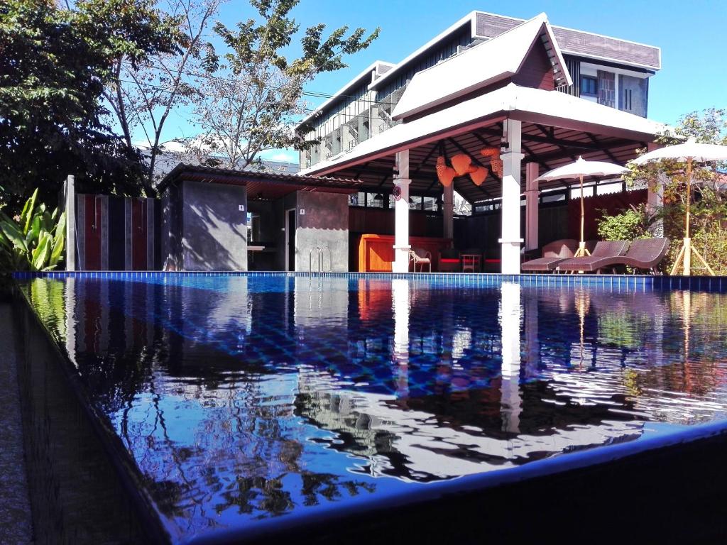 A reflective outdoor pool facing a covered seating area and the hotel building.