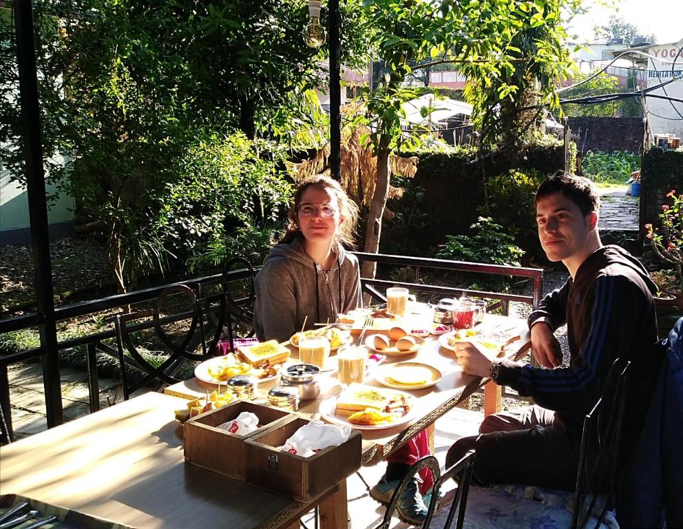 un uomo e una donna seduti a un tavolo con del cibo di Yeti Guest House a Pokhara