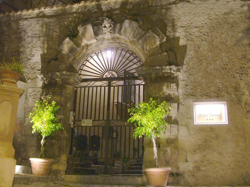 a gate in a stone building with two potted plants at Hotel Relais Modica in Modica