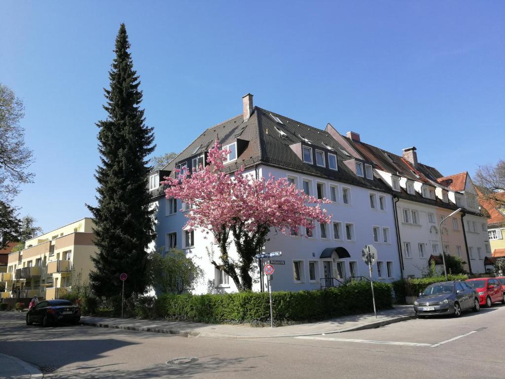 ein weißes Gebäude mit einem blühenden Baum davor in der Unterkunft Boardinghouse München-Laim in München