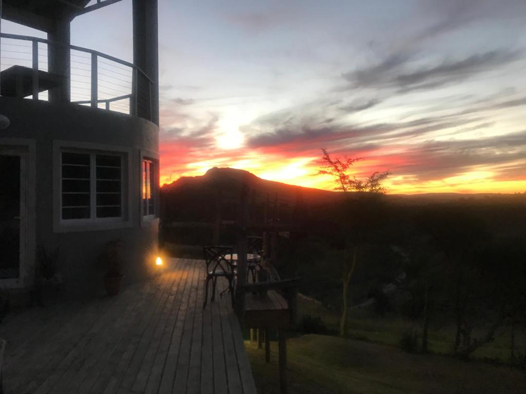 a sunset from a house with the sun setting in the background at A Stone's Throw Accommodation in Grahamstown
