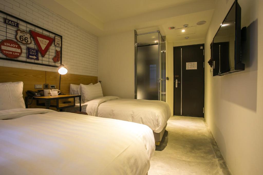 a hotel room with two beds and a table and a door at Re-Change Hotel Taipei in Taipei
