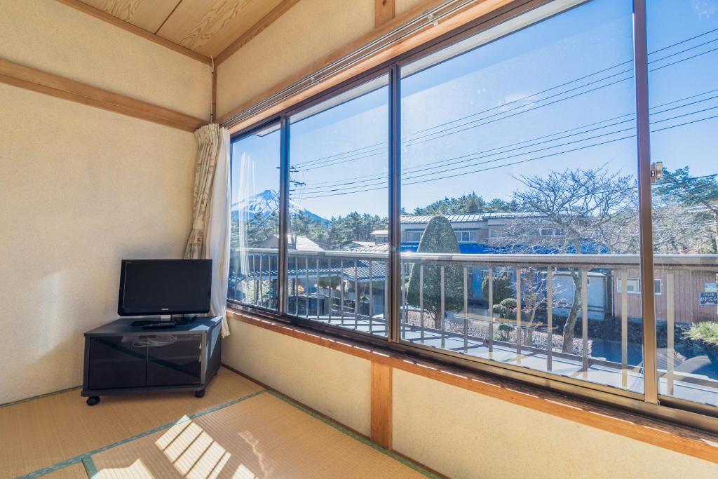 a room with a large window and a television at Cyokiya Lake Saiko in Fujikawaguchiko