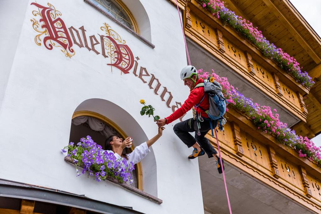 a man climbing onto the side of a building with a woman at Hotel Vienna in San Martino di Castrozza